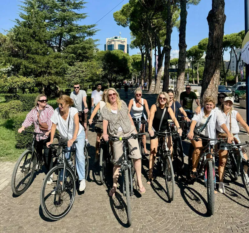 En gruppe smilende kvinder cykler ad en trækantet sti